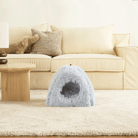 Kuschelige blaue Haustierhöhle auf Teppich vor beigem Sofa, gemütliches Tierbett, Wohnzimmerdekor.