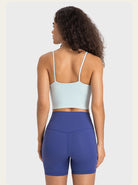Frau in Sportbekleidung: hellblaues Top, blaue Shorts. Ideal für Fitness, Yoga, Laufen. Bequeme, atmungsaktive Materialien für aktive Frauen.