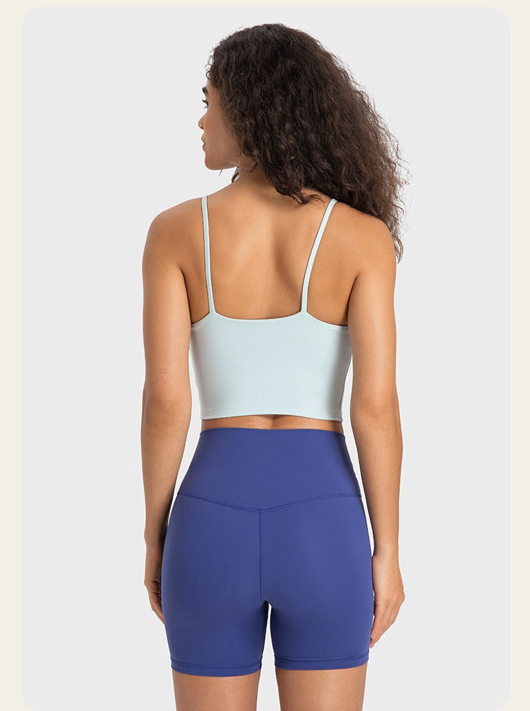 Frau in Sportbekleidung: hellblaues Top, blaue Shorts. Ideal für Fitness, Yoga, Laufen. Bequeme, atmungsaktive Materialien für aktive Frauen.