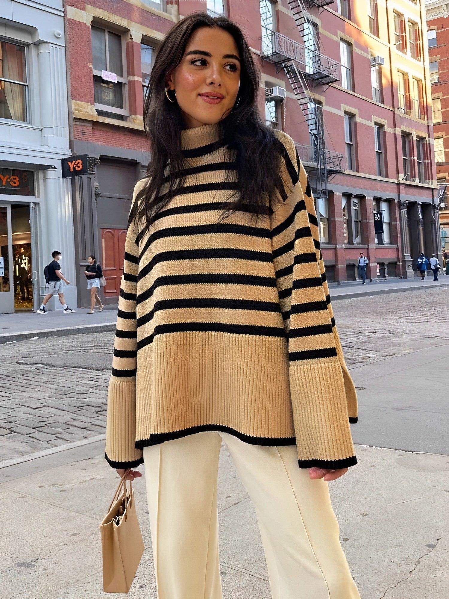 Frau in gestreiftem Pullover und weißer Hose auf städtischer Straße. Modetrend, Herbstmode, Streetstyle, elegantes Outfit, Damenbekleidung.