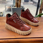 Braune Leder-Sneaker mit dicker, geriffelter Sohle auf Holztisch. Modische, bequeme Schuhe für Damen und Herren. Ideal für Freizeit und Alltag.