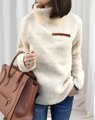 Damen Teddy-Fleece-Pullover in Weiß, kombiniert mit brauner Lederhandtasche. Modischer, kuscheliger Look für Herbst und Winter.