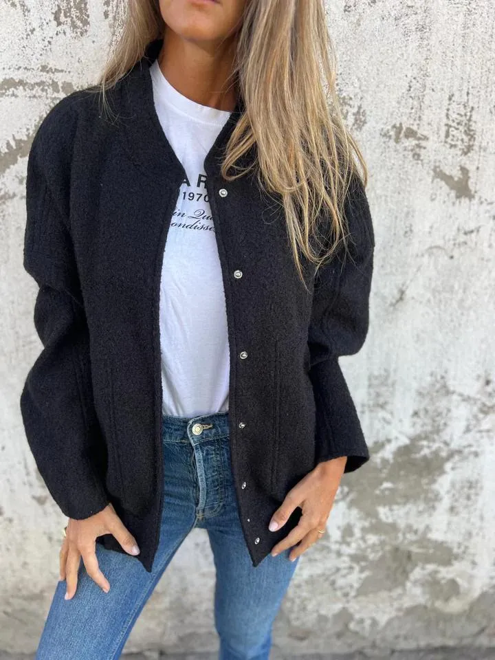 Damenmode: Schwarze Strickjacke, lässig über weißem T-Shirt und blauer Jeans getragen. Trendige Herbstmode, stilvoll und bequem.