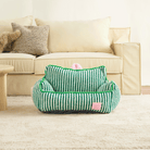 Grünes gestreiftes Haustiersofa vor beigem Sofa, gemütliches Design, Wohnzimmer.