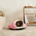 Kuscheliges rosa Haustierbett mit Hund, Höhlenform, weiches Material, Wohnzimmer.