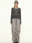 Frau in grauem Langarmshirt mit Schriftzug, weiten Cargo-Hosen und Mütze. Modetrend, urbaner Stil, lässige Damenbekleidung.