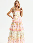 Langes, ärmelloses Sommerkleid mit floralem Muster, rosa Akzenten und Rüschen. Perfekt für elegante Anlässe und modische Sommerlooks.
