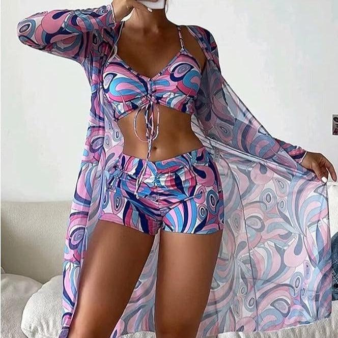 Frau in farbenfrohem, gemustertem Strandoutfit mit Kimono, Top und Shorts. Sommermode, Boho-Stil, trendige Bademode, lebendige Muster.