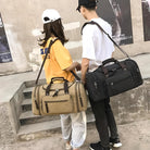 Zwei Personen mit Reisetaschen aus Canvas, beige und schwarz, lässiger Stil, Outdoor-Mode.