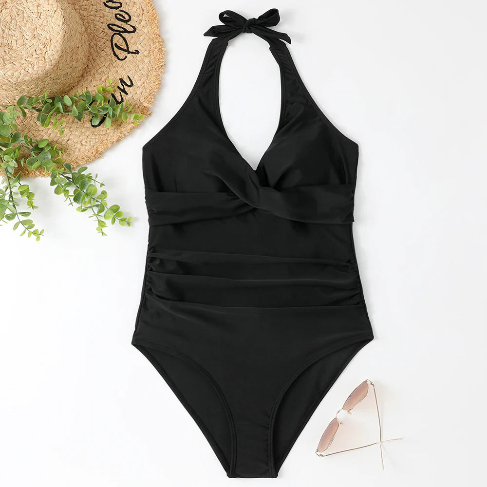 Schwarzer Badeanzug mit Neckholder-Design, eleganter Schnitt, ideal für Strandmode. Perfekt kombiniert mit Strohhut und Sonnenbrille.