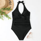 Schwarzer Badeanzug mit Neckholder-Design, eleganter Schnitt, ideal für Strandmode. Perfekt kombiniert mit Strohhut und Sonnenbrille.