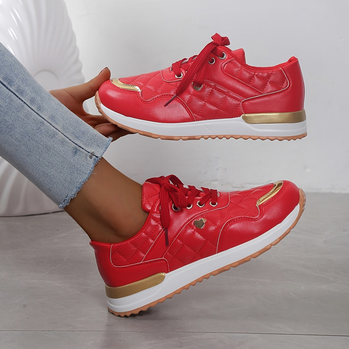 Rote Damen-Sneaker mit goldenen Akzenten, gepolstertem Design und weißer Sohle. Modische Sportschuhe, ideal für Freizeit und Sport.