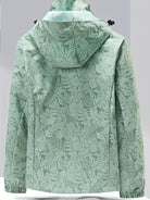 Damen-Regenjacke in Mintgrün mit tropischem Blattmuster, wasserdicht, atmungsaktiv, ideal für Outdoor-Aktivitäten und modische Freizeitkleidung.