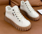 Weiße Sneaker mit dicker, brauner Sohle auf braunem Hintergrund. Modische Damen-Schuhe, ideal für Freizeit und Streetwear.