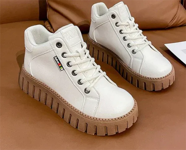 Weiße Sneaker mit dicker, brauner Sohle auf braunem Hintergrund. Modische Damen-Schuhe, ideal für Freizeit und Streetwear.