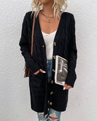 Damen Strickjacke schwarz, lang, mit Zopfmuster und Knöpfen, kombiniert mit weißem Top und zerrissenen Jeans. Modetrend Herbst 2023.