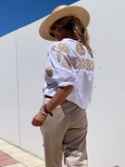 Frau in weißer bestickter Bluse und Strohhut, beige Hose, Sommermode, Outdoor.