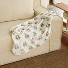 Weiße Kuscheldecke mit Bärenmuster auf beigem Sofa, weiche Haustierdecke, Wohnzimmer.