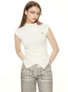 Frau in weißem ärmellosen Oberteil und grauer Hose, trägt Brille. Modetrend, Damenmode, eleganter Look, stilvolle Kleidung, Fashion-Fotografie.