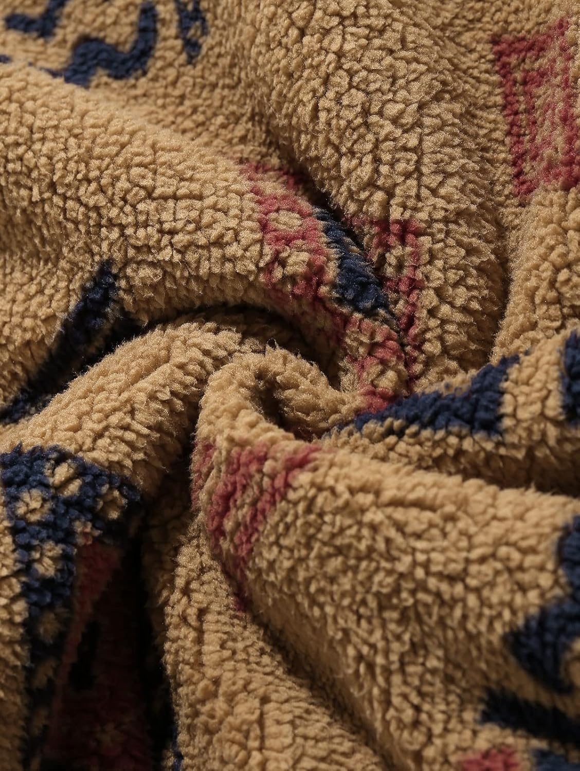 Beigefarbener Fleece-Stoff mit blau-rotem Muster, weiche Textur, ideal für warme Kleidung.