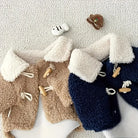 Zwei Babyjacken aus Teddyfleece in Beige und Blau mit Holzknöpfen und weißen Kragen, ideal für Herbstmode. Kuschelig, stilvoll, warm.