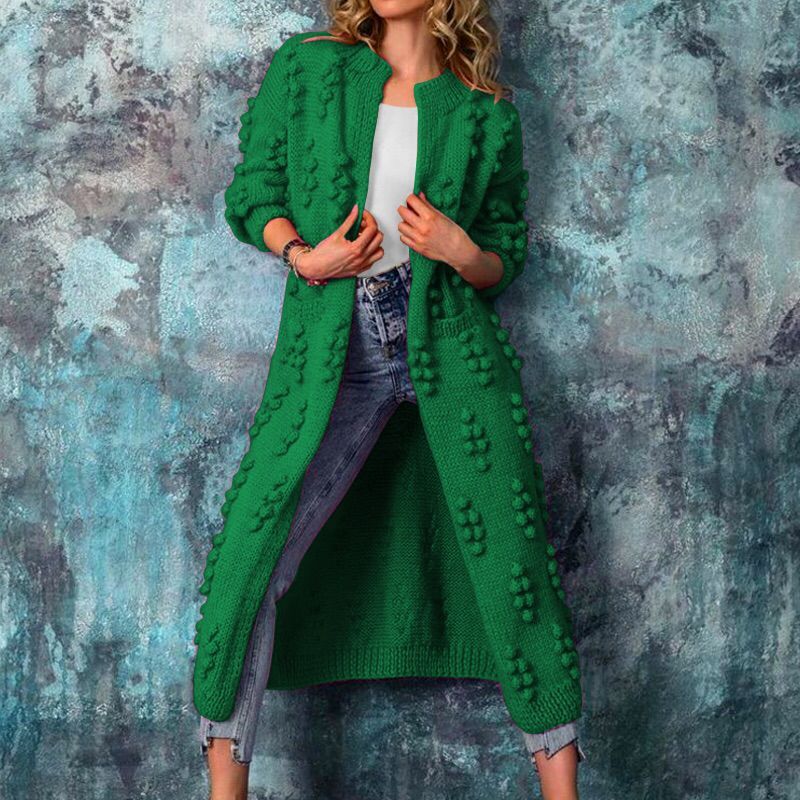Grüner Strickmantel mit 3D-Punkten, lässig über Jeans und weißem Top getragen. Modetrend, Damenmode, Herbstoutfit, Strickmode.