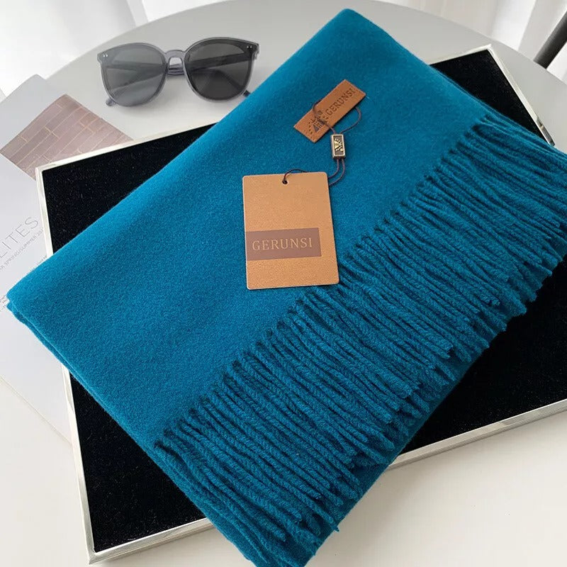Gerunsi Schal aus weichem Kaschmir in Türkis, elegant gefaltet auf schwarzem Hintergrund. Perfekt für stilvolle Wintermode und Accessoires.