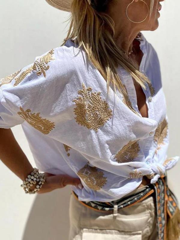 Frau in weißer bestickter Bluse mit goldenen Mustern, Strohhut, Sommermode, lässiger Stil.