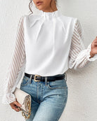 Elegante weiße Bluse mit transparenten Ärmeln und Chevron-Muster, kombiniert mit blauer Jeans. Perfekt für stilvolle Damenmode und Freizeitoutfits.