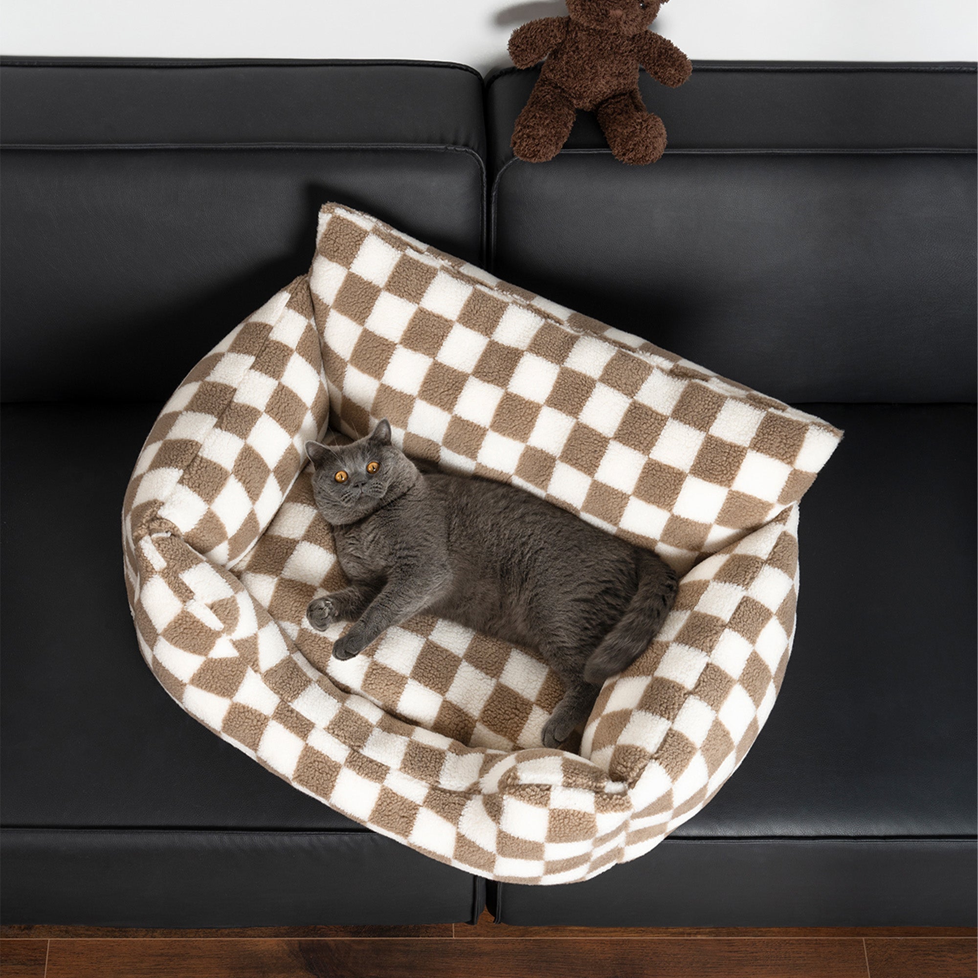 Kariertes Hundesofa, abnehmbar, waschbar, braun-weiß, mit Katze darauf, auf schwarzem Sofa.