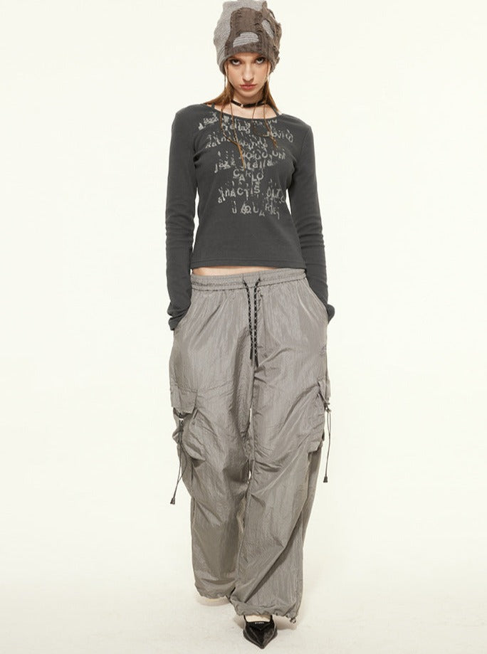 Frau in grauem Langarmshirt und weiten Cargo-Hosen, modischer Streetwear-Look, lässiger Stil, Herbstmode, urbaner Trend, bequeme Kleidung.