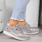 Damen-Sneaker in Silber mit Keilabsatz, kombiniert mit hellblauen Jeans. Modische, bequeme Schuhe für Alltag und Freizeit. Trendige Sneaker 2023.