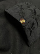 Schwarze Stofftasche mit Knopf, verziert mit floralen Stickereien. Hochwertiges Design, ideal für elegante Mode und Accessoires.