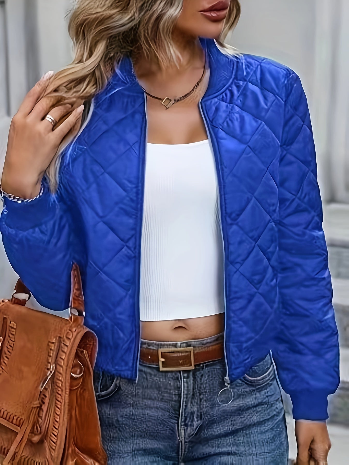Blaue Steppjacke Damenmode, kombiniert mit weißem Top und Jeans. Trendige Herbstbekleidung, ideal für stilvolle Freizeitoutfits.