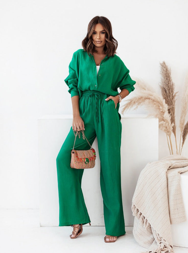 Frau in grünem Jumpsuit posiert stilvoll mit bunter Handtasche. Modetrend, Damenmode, elegantes Outfit, Freizeitlook, Modefotografie.