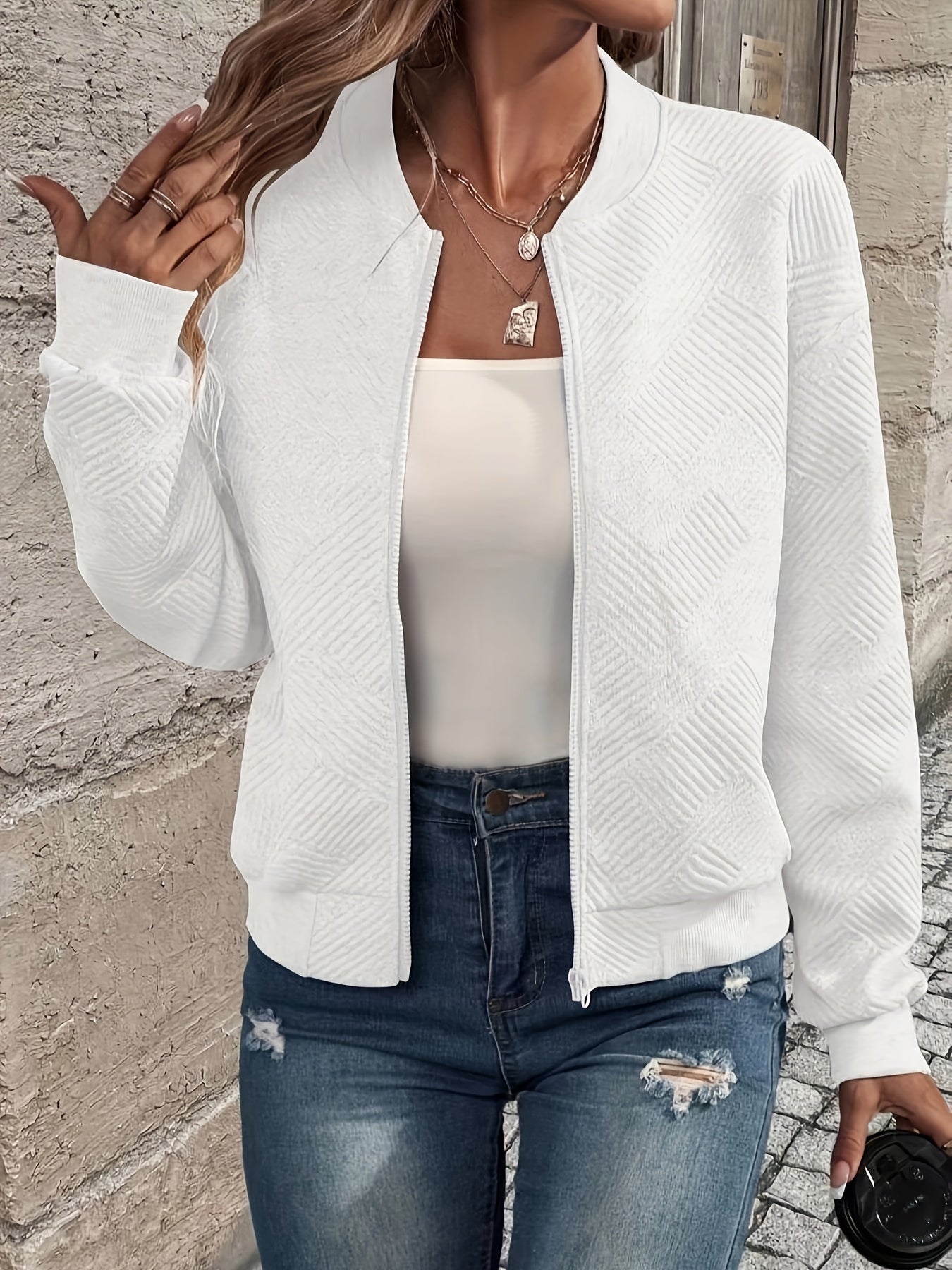 Damenmode: Weiße Strickjacke mit Reißverschluss, kombiniert mit weißem Top und zerrissenen Jeans. Trendige Freizeitkleidung für Frauen.