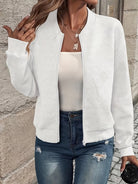 Damenmode: Weiße Strickjacke mit Reißverschluss, kombiniert mit weißem Top und zerrissenen Jeans. Trendige Freizeitkleidung für Frauen.