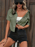 Frau in modischer, grüner Jacke und schwarzer Shorts, trägt Sonnenbrille und Kappe. Trendige Sommermode, lässiger Streetstyle-Look.