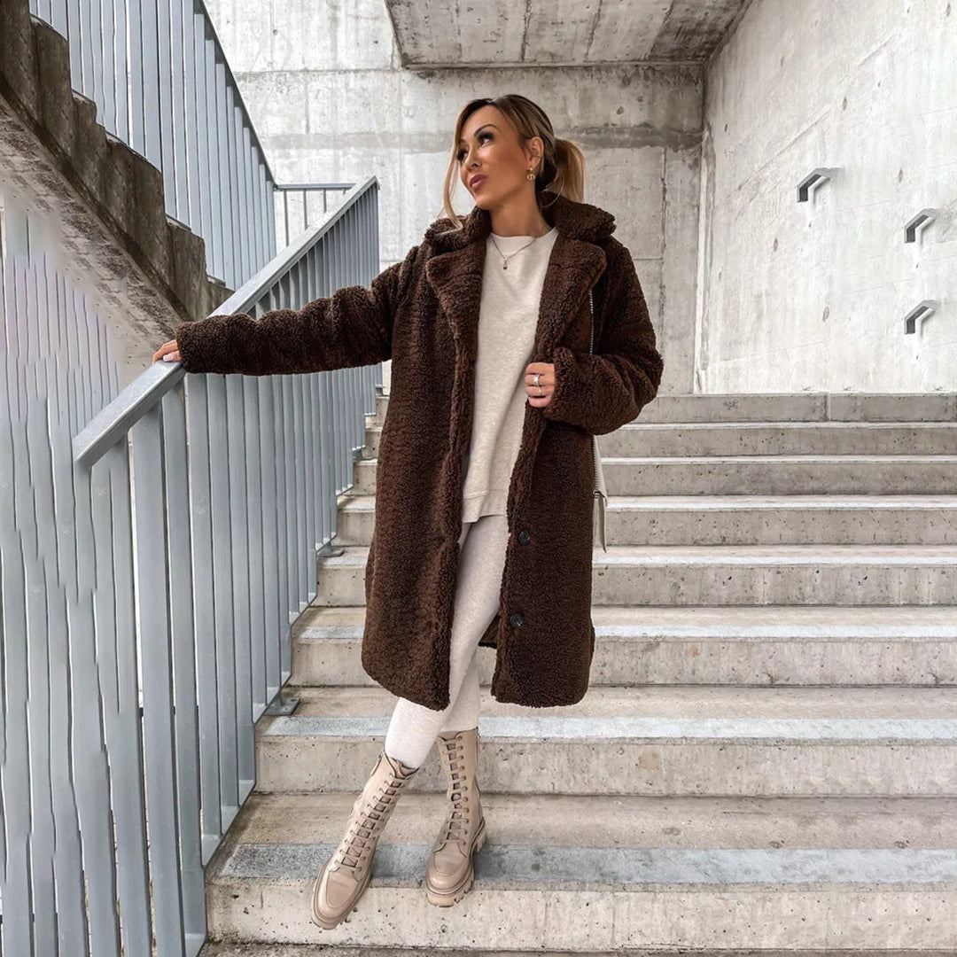 Frau in braunem Teddy-Mantel auf Treppe, modisch und warm. Wintermode, Damenbekleidung, stilvoller Look, Outdoor-Outfit, urbane Eleganz.