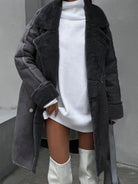 Damenmode: Eleganter grauer Mantel aus Kunstpelz über weißem Strickkleid, kombiniert mit stilvollen weißen Stiefeln. Wintermode, trendig, chic.