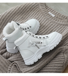 Weiße Winterstiefel mit Fellfutter auf gestricktem Pullover, modische Damen-Sneaker, warm und stilvoll, ideal für kalte Jahreszeiten.