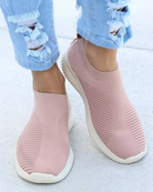 Rosa Slip-On-Sneaker aus atmungsaktivem Strickmaterial, kombiniert mit zerrissenen Jeans. Bequeme, modische Schuhe für Damen.