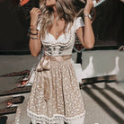 Frau in traditionellem beige Dirndl mit Spitzenmuster und Schleife, Oktoberfest Mode.