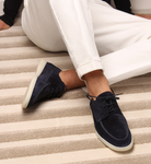 Dunkelblaue Wildleder-Sneaker für Herren, lässig, auf gestreiftem Teppich.