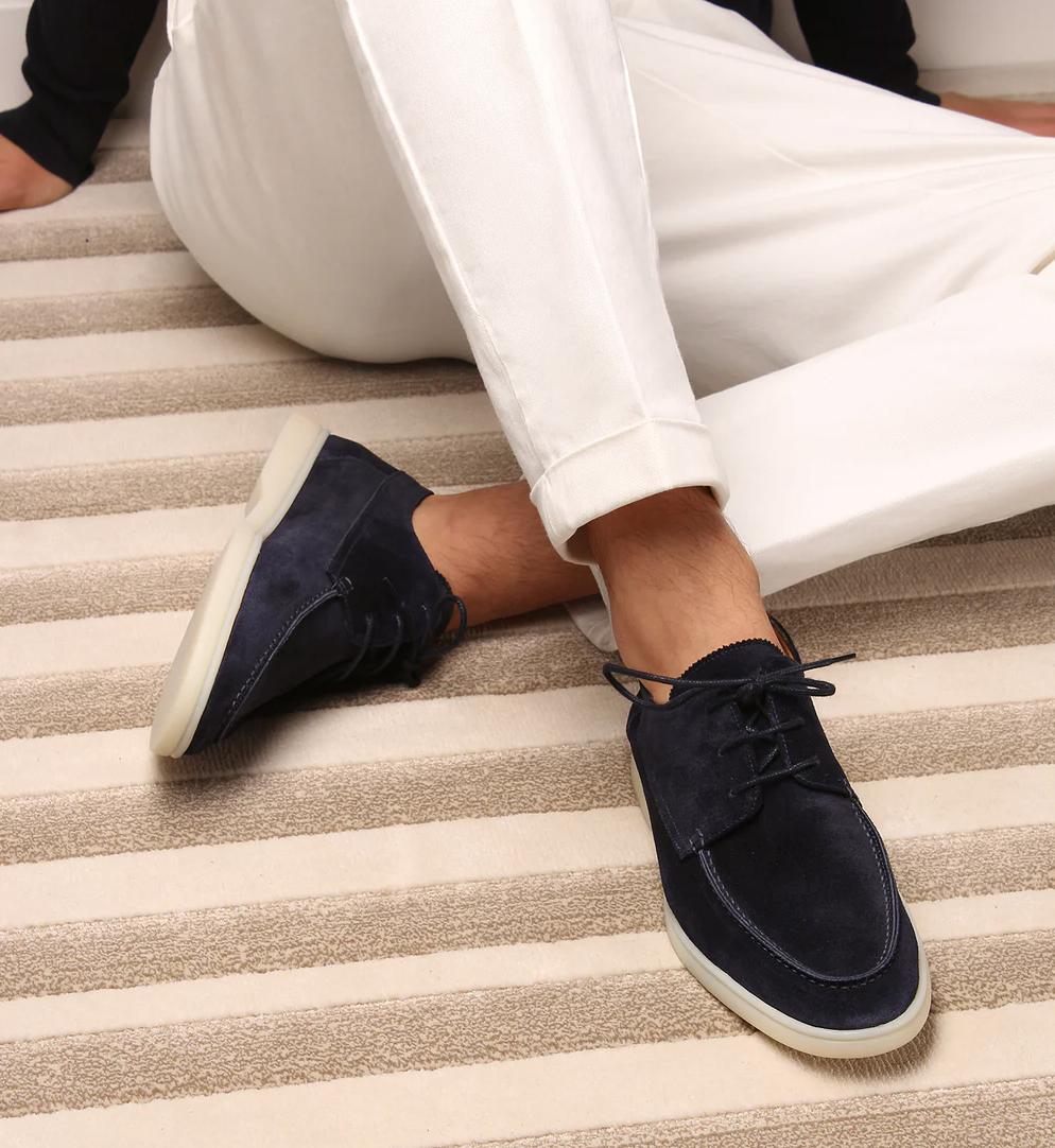 Dunkelblaue Wildleder-Sneaker für Herren, lässig, auf gestreiftem Teppich.
