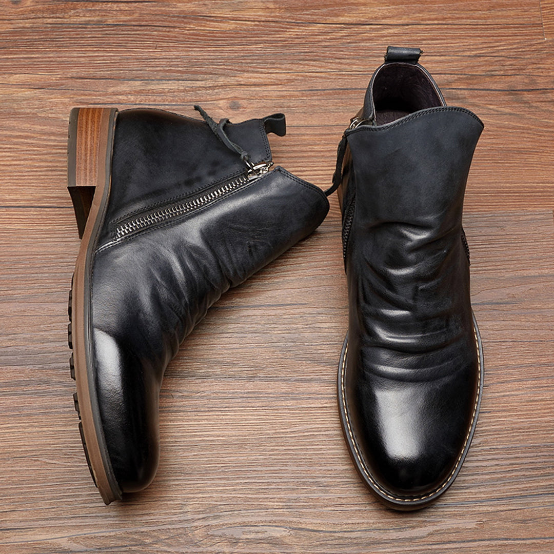 Schwarze Lederstiefeletten mit seitlichem Reißverschluss auf Holzboden. Elegante Damenstiefel, ideal für Herbstmode. Hochwertige Verarbeitung.