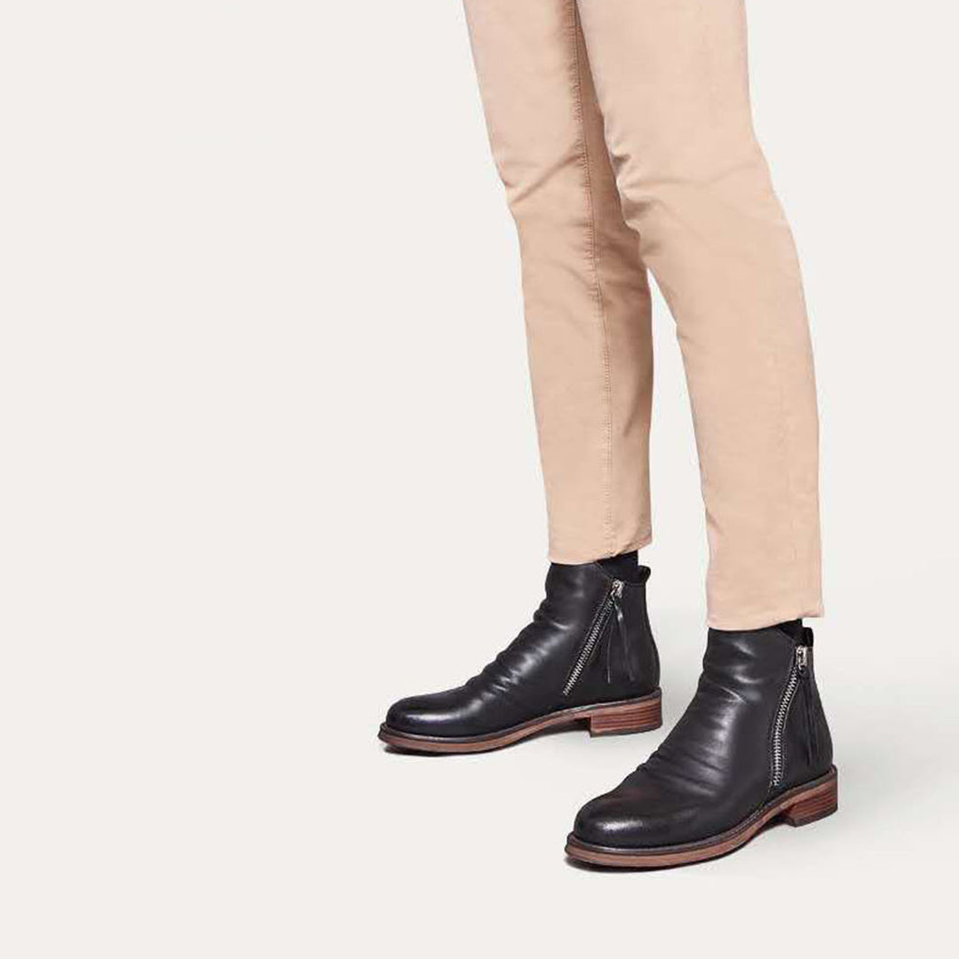 Schwarze Lederstiefel mit Reißverschluss, elegantes Design, kombiniert mit beigefarbenen Hosen. Perfekt für stilvolle Herrenmode und Herbsttrends.