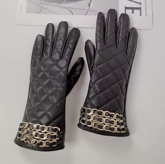 Luxuriöse schwarze Lederhandschuhe mit gestepptem Design und goldenen Kettendetails. Perfekt für stilvolle Wintermode und elegante Outfits.