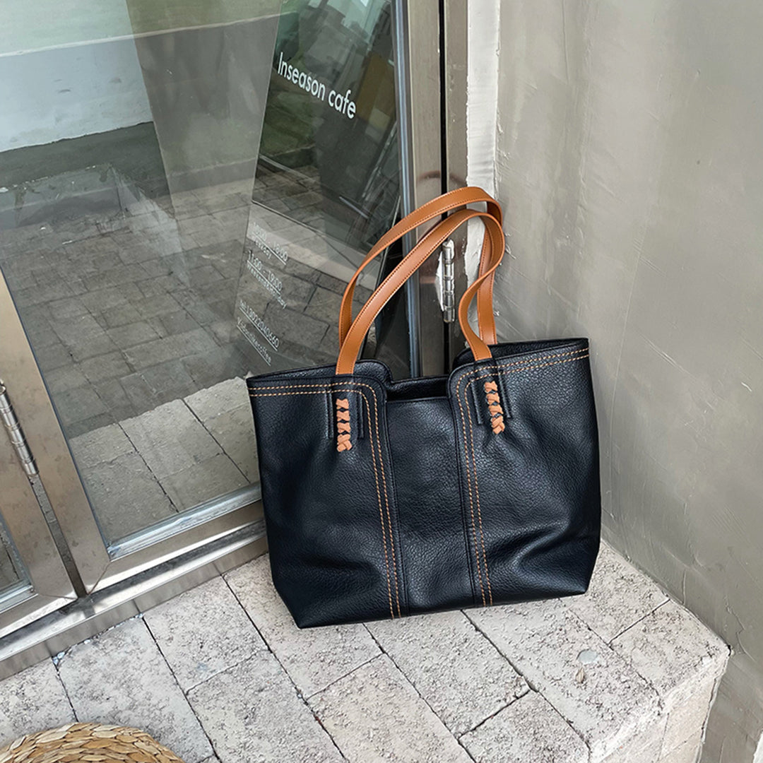 Schwarze Ledertasche mit braunen Griffen, elegant und geräumig, ideal für den Alltag. Perfekt für Modebewusste und stilvolle Auftritte.