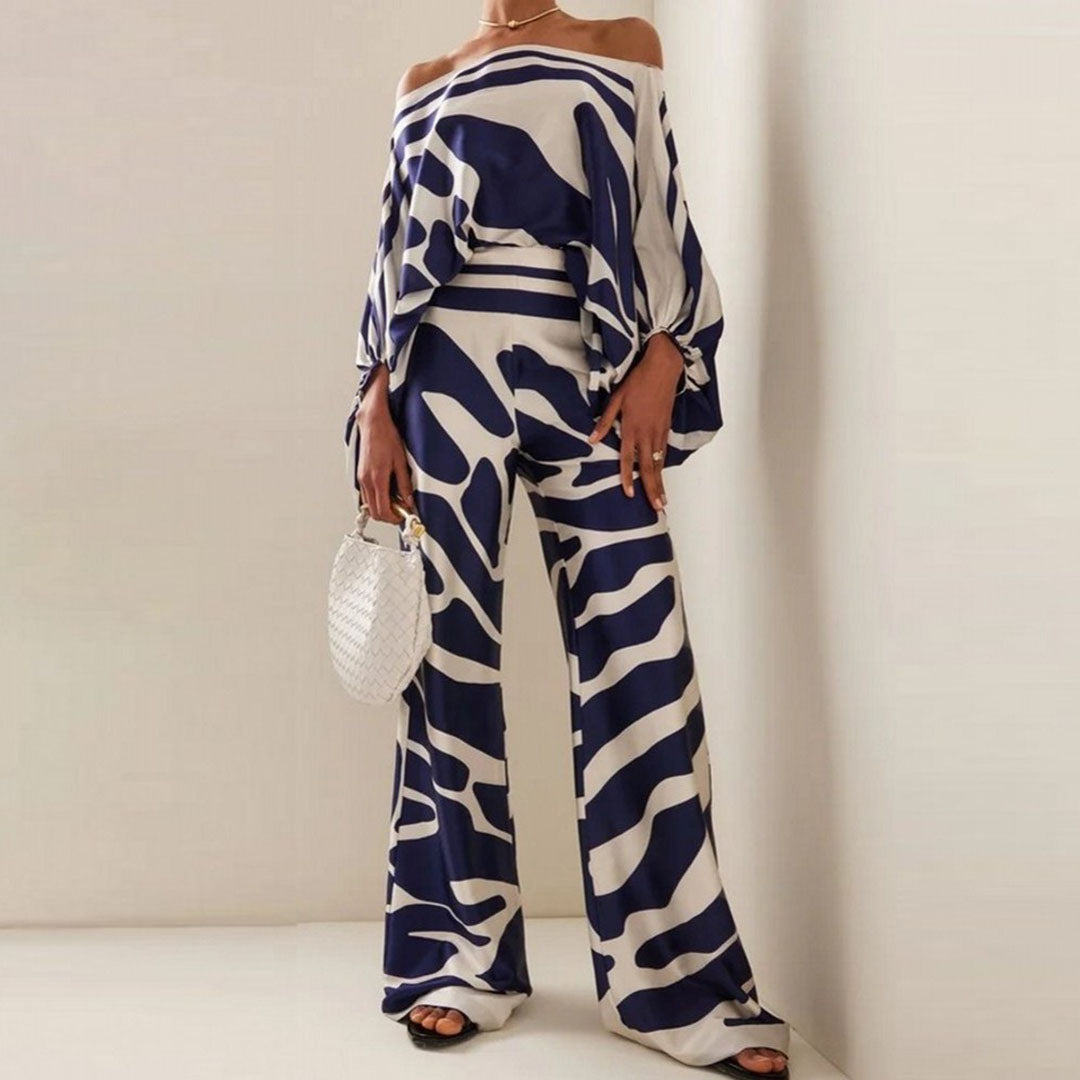 Frau in blau-weißem Zebra-Muster-Outfit, hält weiße Handtasche, modisch, elegant.